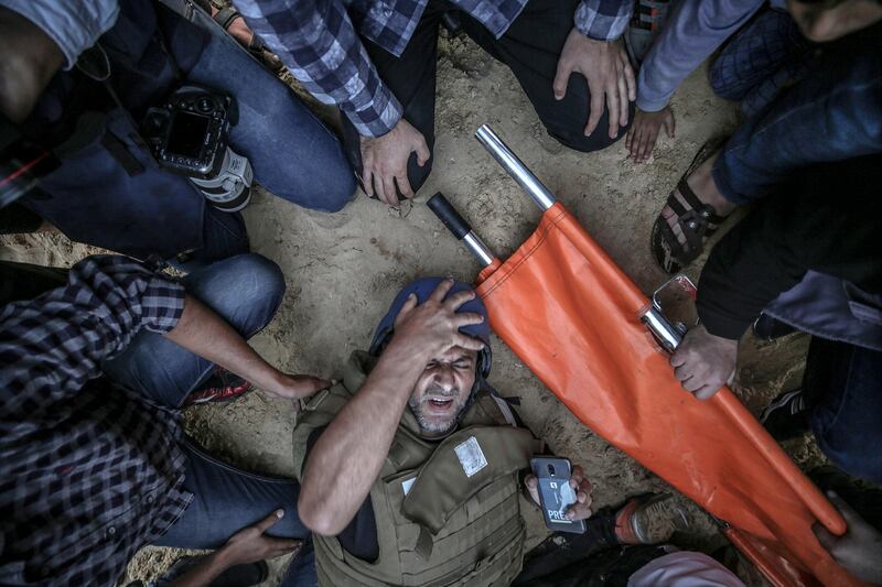 People try to help a cameraman after he was injured by an Israeli sniper during the clashes in the northern Gaza Strip. EPA