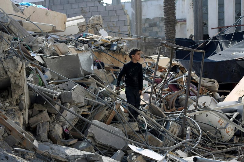 A boy searches for their family's belongings amid the rubble of a destroyed building in Gaza City. AP Photo