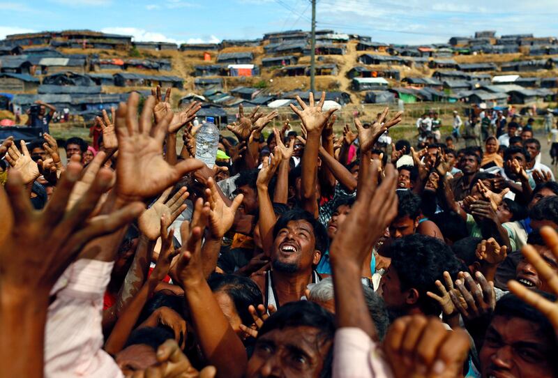 Rohingya refugees stretch their hands to receive aid at the Balukhali makeshift refugee camp in Cox's Bazar, Bangladesh in 2017.