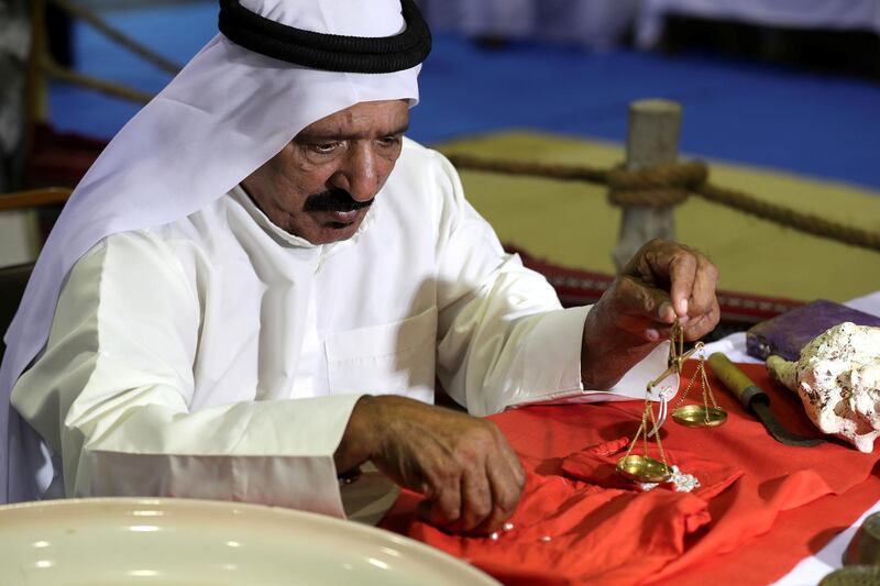 Dibba, United Arab Emirates - June 26, 2019: A man weights pearls. Al Hosn fish salting festival. Wednesday the 26th of June 2019. Dibba. Chris Whiteoak / The National