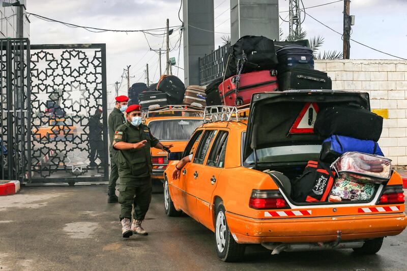 Palestinian border guards, wearing protective face masks due to the COVID-19 pandemic, check the ID of travellers as they wait their turn to cross into Egypt through the Rafah border crossing from the Gaza Strip.  AFP