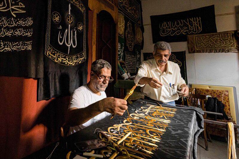 Embroiderer Ahmed Othman El Kassabgy, right, whose family produces the Kiswa, the cloth used to cover the Kaaba at the Grand Mosque, supervises an employee who works on a replica drape to be sold as a souvenir in Cairo, Egypt. AFP