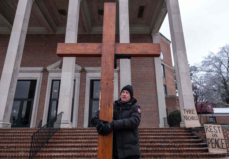 A mourner holds a cross outside of Mississippi Boulevard Christian Church before the funeral. AFP