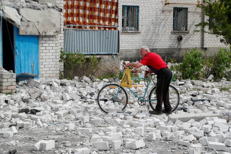 A man pushes a bicycle near a residential building in Rubizhne that was destroyed during fighting between Ukrainian and Russian forces. Reuters