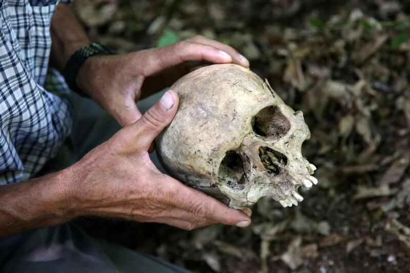 Srebrenica genocide survivor Ramiz Nukic looks at a skull that he found in the forest near Konjevic Polje, Bosnia and Herzegovina July 6, 2020. Nukic has made himself a promise, he will search for the remains of the people who went missing until the last of them is found. Reuters