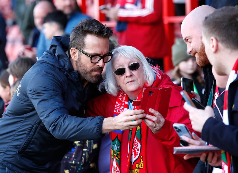 A fan takes a photo with Wrexham co-owner Ryan Reynolds before the match. Reuters