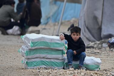 A displaced Syrian boy sits next to humanitarian aid at a camp along the border with Turkey. AFP