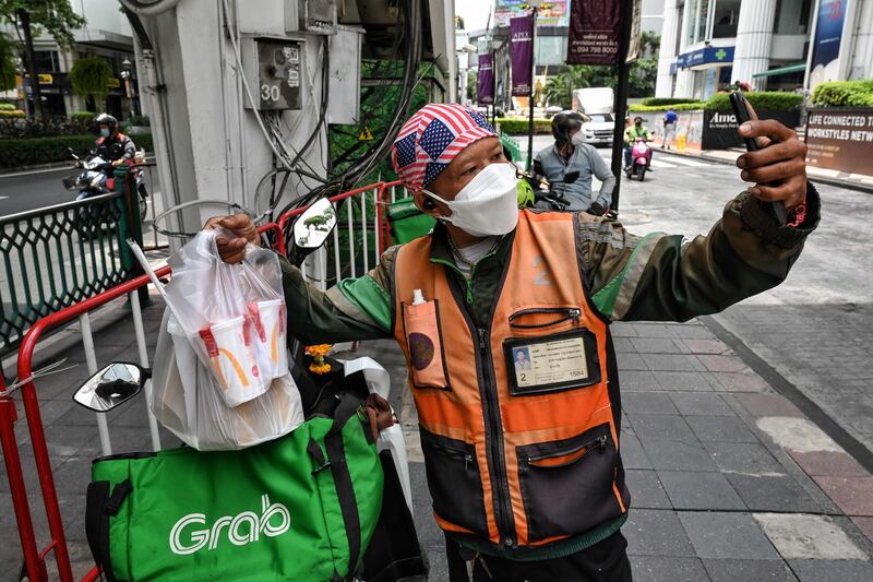 A GrabFood delivery driver takes a selfie after picking up orders of the limited edition K-pop band "BTS Meal" from a McDonald's branch in Bangkok on July 16. AFP