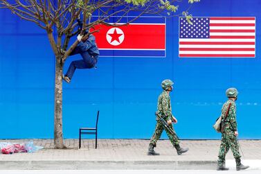 A worker is seen on a tree next to a banner showing North Korean and U.S. flags ahead of the North Korea-U.S. summit in Hanoi, Vietnam, February 25, 2019. REUTERS/Kim Kyung-Hoon