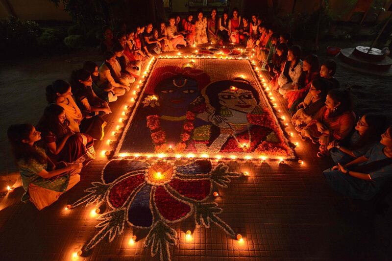 Indian girls light earthen lamps on a Rangoli as they celebrate Diwali in Guwahati.  AFP