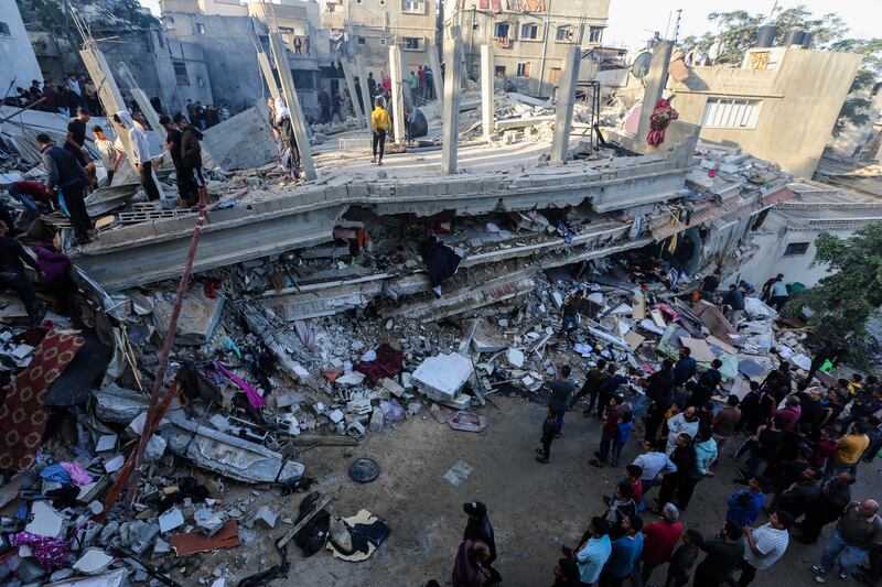 People search through buildings, destroyed during Israeli air strikes in Khan Younis, Gaza. Getty Images