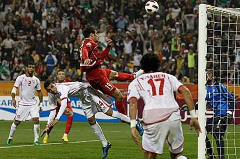 Iran's Mohammad Gholami's shot at goal hits the crossbar, next to United Arab Emirates' Walid Abbas (No 14).