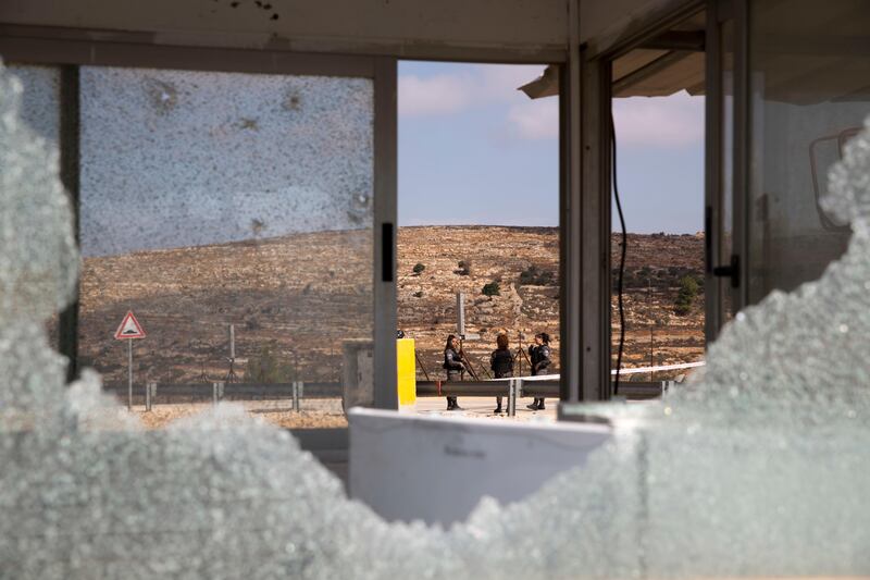 Israeli security officers are seen through bullets shattered windows of the check point at the entrance to Har Adar settlement near Jerusalem. Ariel Schalit / AP Photo