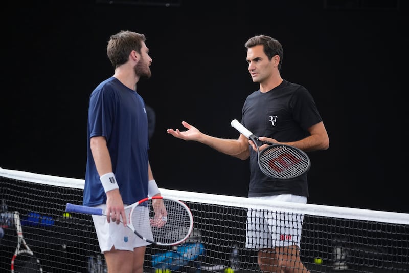 Roger Federer chats with Cameron Norris of Great Britain during a training session in London. AP