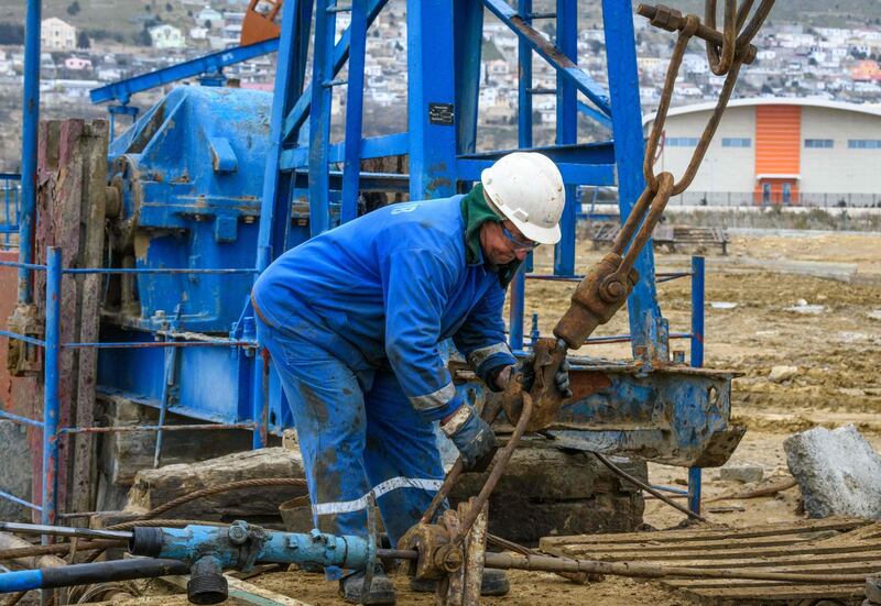 A worker mounts a pump jack at Bibi Heybat Oil Field, situated at the coast of the Caspian Sea outside Baku on March 19, 2019. Bibi Heybat's first oil drill took place in 1847, making it the oldest oil field in the world, allegedly 13 years before the first oil well was drilled in the United States. / AFP / Mladen ANTONOV
