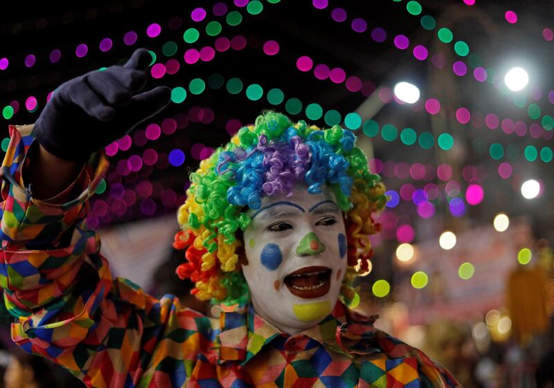 A man dressed in a clown costume attracts customers to a store in a market on the eve of Diwali in New Delhi, India. Reuters