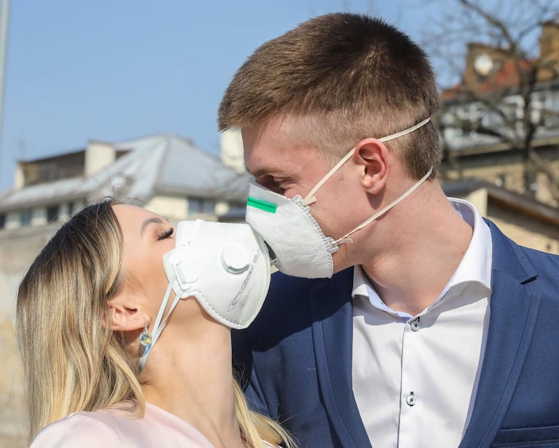 Lithuanian groom Dainius and his bride Ramune pose for the photographer, wearing protective masks against the new coronavirus after their wedding ceremony in Vilnius, Lithuania.   AFP