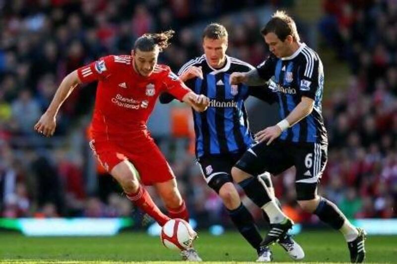 Liverpool's Andy Carroll, left, fends off Stoke duo Glenn Whelan and Robert Huth. Alex Livesey / Getty Images