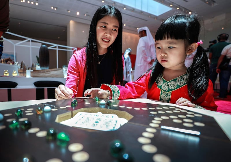 Abu Dhabi, U.A.E., July 17, 2018.   The Launch of China Week at Manarat Al Saadiyat with guests of honor, Noura Al Kaabi, Minister of Culture and Knowledge Development and Ni Jian, Ambassador of China.  --  A little girl plays with the Chinese Checkers game at the exhibition.
 Victor Besa / The National
Section:  NA
Reporter:  John Dennehy