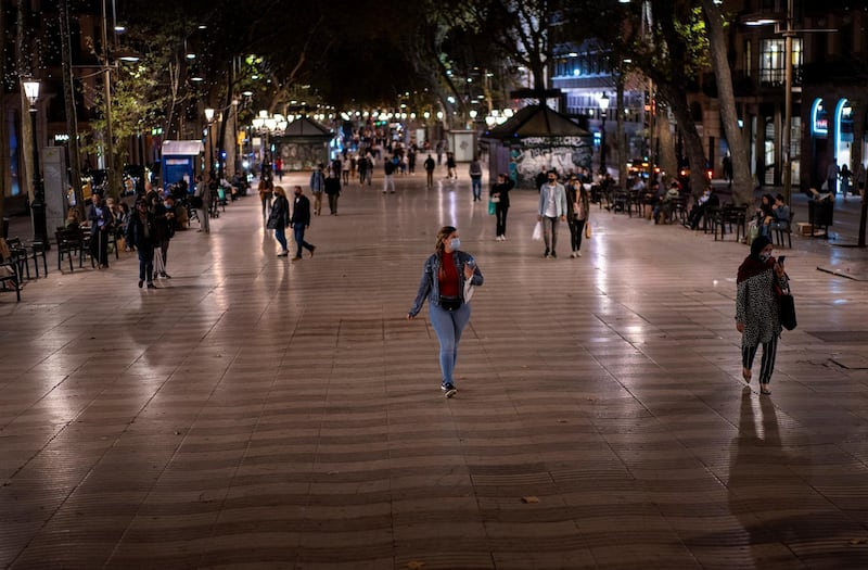 Pedestrians walk along Las Ramblas of Barcelona, where terraces, restaurants and bar are closed due to the sharpest resurgence of the  coronavirus. AP