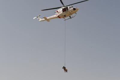 A policeman is suspended from a helicopter, with a K9 dog in tow. Courtesy Dubai Police