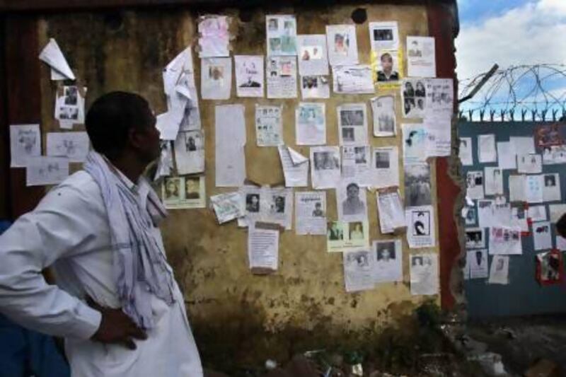 An Indian man looks at a wall covered in special announcements and pictures of missing people near the airport gate in Jollygrant, in northern Indian state of Uttarakhand.