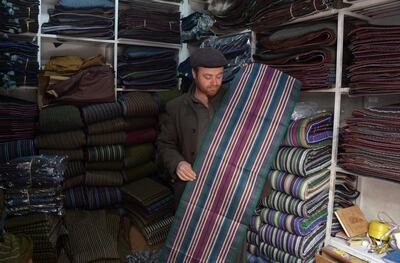 In this photo taken on March 10, 2018, an Afghan shopkeeper and provincial contractor of Zarif Design House shows fabrics to made a chapan (coat) at his shop in Mazar-i-Sharif.
Cheap, Chinese-made nylon burkas are flooding Afghanistan's north as consumers turn to affordable, mass-produced fabrics -- but in Kabul a small, determined fashion house is fighting to preserve the traditional textiles once integral to Afghan culture.
 / AFP PHOTO / FARSHAD USYAN / TO GO WITH Afghanistan-lifestyle-social-fashion,FEATURE by Anne Chaon
