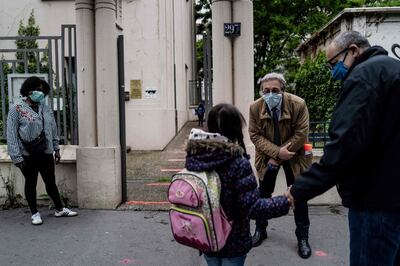 The school director welcomes every pupils as they arrive at school on its reopening day, on May 14, 2020 at a school in Lyon, as primary schools in France re-open this week and the country eases lockdown measures taken to curb the spread of the COVID-19 (the novel coronavirus). / AFP / JEFF PACHOUD
