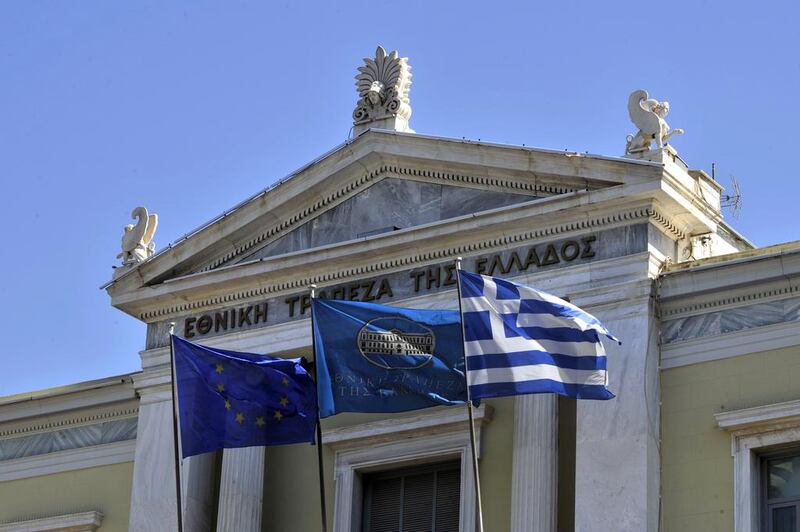 EU, National Bank and Greek flags float in front of the facade of the headquarters of the National Bank of Greece. AFP