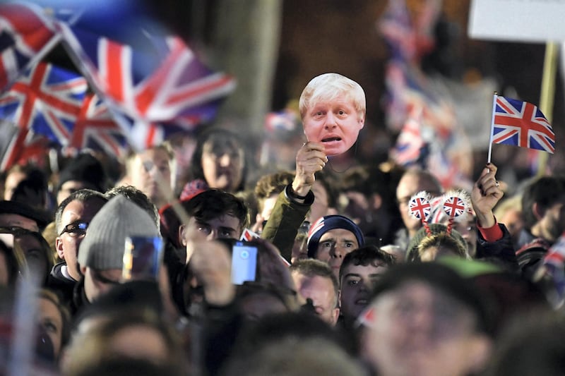 Brexit supporters wave Union flags ans a mask of Britain's Prime Minister Boris Johnson as the time reaches 11 O'Clock, in Parliament Square, venue for the Leave Means Leave Brexit Celebration in central London on January 31, 2020, the moment that the UK formally leaft the European Union. - Brexit supporters gathered outside parliament on Friday to cheer Britain's departure from the European Union following three years of epic political drama -- but for others there were only tears. After 47 years in the European fold, the country leaves the EU at 11:00pm (2300 GMT) on Friday, with a handful of the most enthusiastic supporters gathering opposite the Houses of Parliament 12 hours before the final countdown. (Photo by DANIEL LEAL-OLIVAS / AFP)
