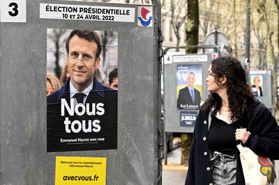 A pedestrian walks past a campaign poster of France's President and La Republique en Marche party candidate Emmanuel Macron. AFP
