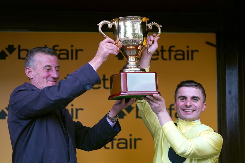 Andrea Atzeni, right, and trainer Kevin Ryan lift the trophy after winning the Sprint Cup Stakes on Emaraaty Ana at Haydock Park racecourse. PA