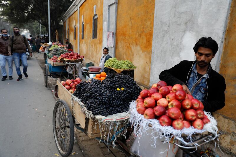 A fruit vendor waits for customers at a market in Lucknow, India. Friday, Jan. 29, 2021. India's economy contracted by 7.7% in the 2020-21 financial year, battered by the coronavirus pandemic, according to a report released Friday. (AP Photo/Rajesh Kumar Singh)