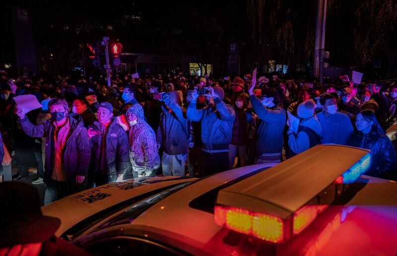 Protesters march past a police vehicle during  a demonstration against China's strict zero-Covid measures, in Beijing. Getty