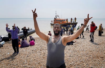 A man gestures as migrants arrived on the beach before later being taken away by Border Force staff. AP