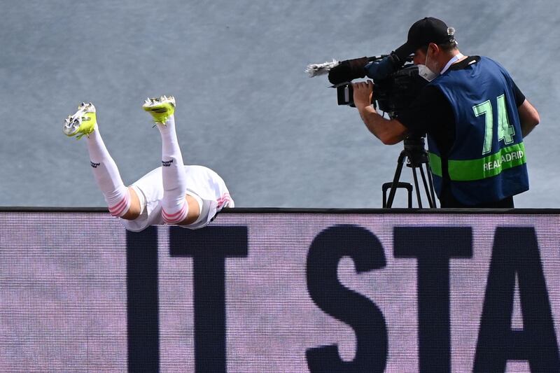 Real Madrid's French forward Karim Benzema falls over the advertisement boards. AFP