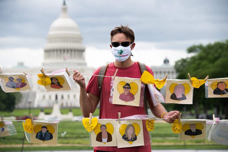 Christopher Edwards holds up a memorial to those who died from Covid-19, including his grandmother, Brenda Meadows, in Washington, May 5, 2021. AFP