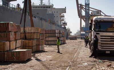 This picture taken on March 14, 2021 shows pallets of imported wood being unloaded off a cargo ship on the pier at the port of Umm Qasr, south of Iraq's southern city of Basra. Iraq is ranked the 21st most corrupt country by Transparency International. In January, the advocacy group said public corruption had deprived Iraqis of basic rights and services, including water, health care, electricity and jobs. It said systemic graft was eating away at Iraqis' hopes for the future, pushing growing numbers to try to emigrate. In 2019, hundreds of thousands of protesters flooded Iraqi cities, first railing against poor public services, then explicitly accusing politicians of plundering resources meant for the people. / AFP / Hussein FALEH
