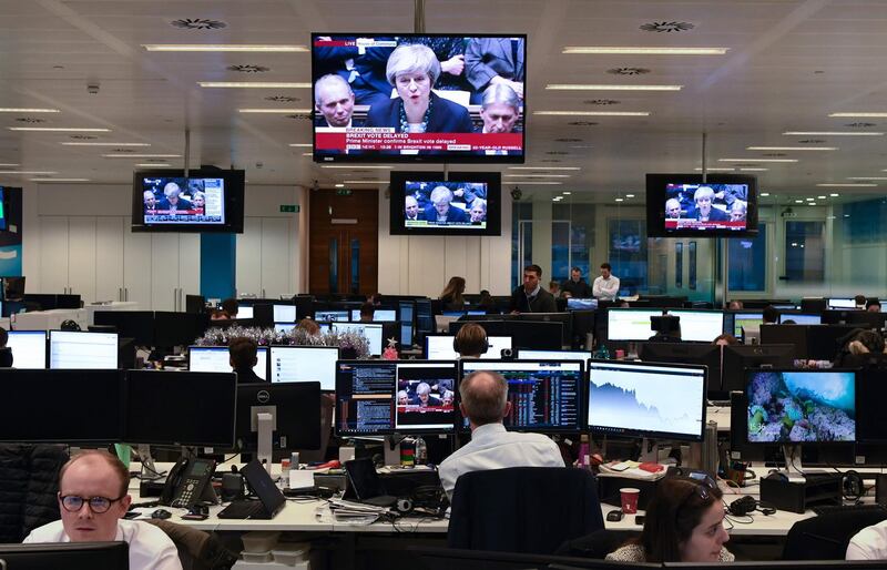 Traders work at the offices of CMC Markets in the City of London on December 10, 2018 as Britain's Prime Minister Theresa May makes a statement in the House of Commons announcing the government's intention to delay the 'meaningful' vote on the Brexit withdrawl agreement. British Prime Minister Theresa May on December 10, 2018 postponed a parliamentary vote on her Brexit deal to avoid a crushing defeat, saying she would return to the EU for further talks in a perceived sign of weakness that sent the pound plunging. / AFP / Daniel SORABJI

