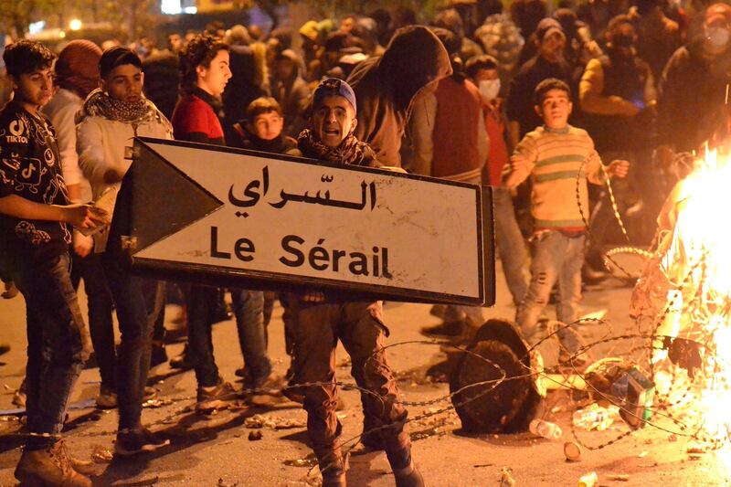 A Lebanese anti-government protester holds a sign of the Serail, the headquarters of the Governorate of North Lebanon, in the northern port city of Tripoli. AFP