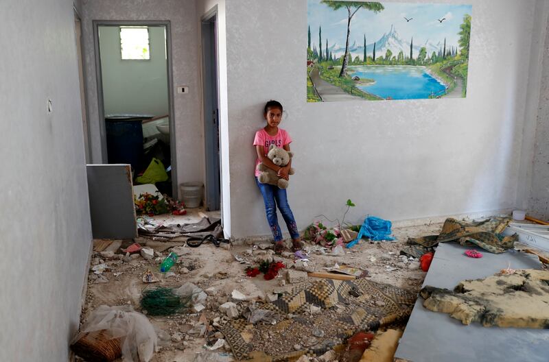 Rahaf Abu Fares, 10, who lost four family members when an Israeli artillery bombardment hit his family home in May, carries a teddy bear amid the rubble of his house, at the Bedouin village of Umm Al-Nasr in the northern Gaza Strip.  After initially finding no grounds for disciplinary action, the Israeli military says it is investigating the artillery bombardment that killed six Palestinians, including an infant. AP Photo