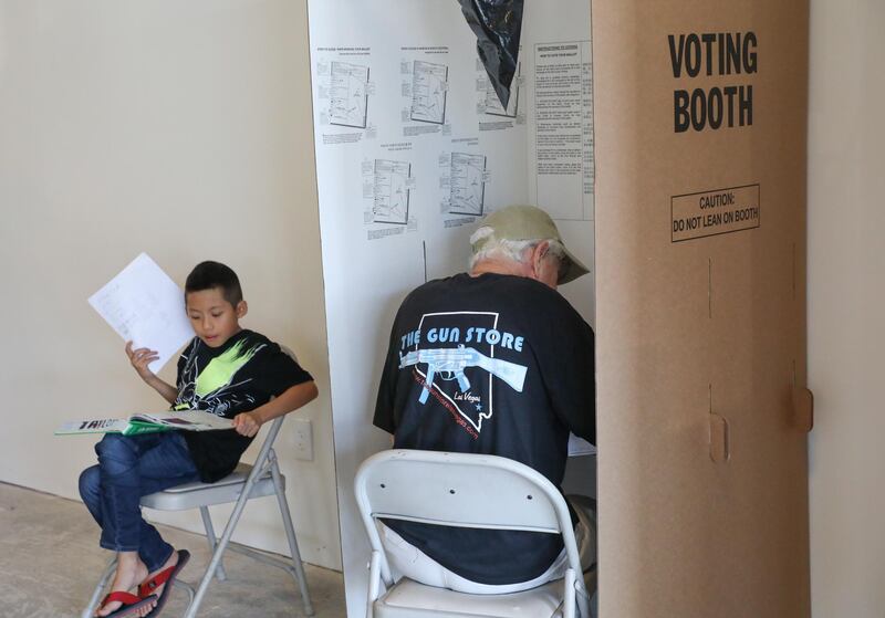 An early voter (right) casts his ballot as another's child waits doing homework, during early voting at a polling station in Huntington Beach, California. EPA