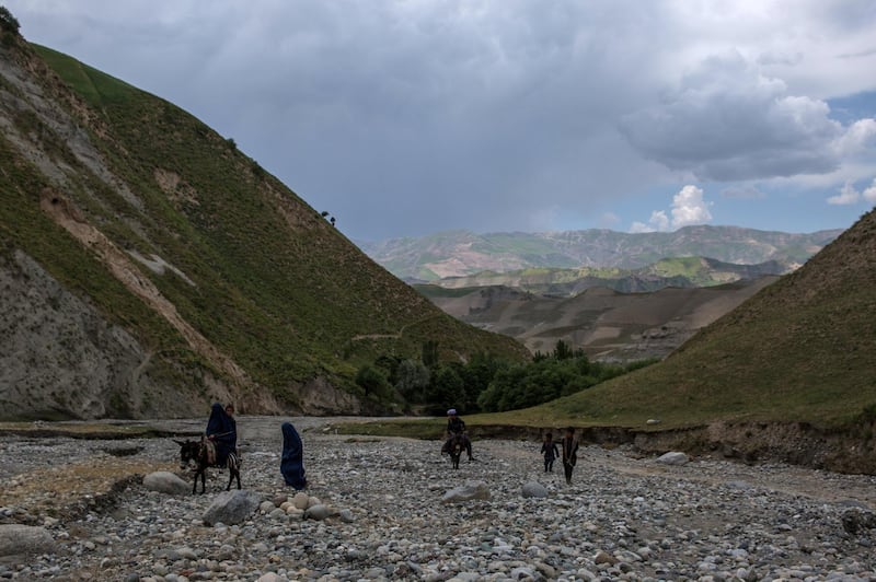 Villagers near Khaja Gulrang in Afghanistan's Badakhshan province return home, walking through an empty river bed. 