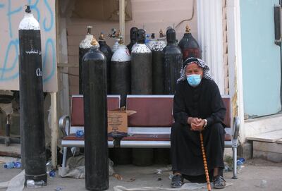 An Iraqi man waits next to oxygen bottles for his wife who is a patient with COVID-19 at the Ibn Al-Khatib Hospital in Baghdad, on April 25, 2021, after a fire erupted in the medical facility reserved for the most severe coronavirus cases. At least 23 people died when a fire broke out in a coronavirus intensive care unit in the capital of Iraq, a country with long-dilapidated health infrastructure facing mounting COVID-19 cases. / AFP / AHMAD AL-RUBAYE
