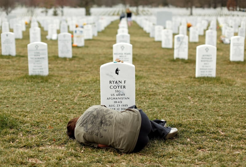Lesleigh Coyer, of Saginaw, Michigan, lies down in front of the grave of her brother, Ryan Coyer, who served with the US Army in both Iraq and Afghanistan, at Arlington National Cemetery in Virginia, US, March 11, 2013. Reuters