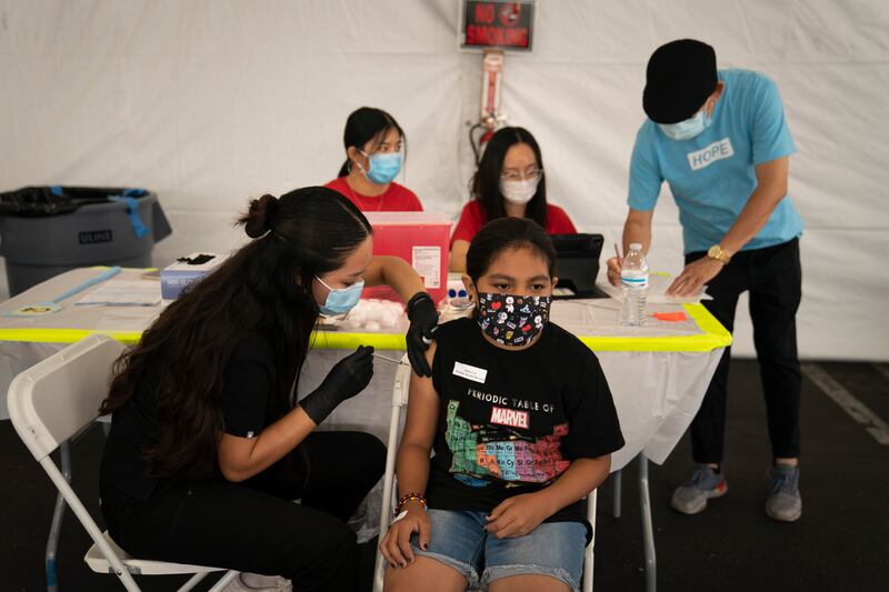 Mayra Navarrete, 13, receives the Pfizer Covid-19 vaccine from registered nurse, Noleen Nobleza at a clinic set up in the parking lot of CalOptima in Orange, California. AP