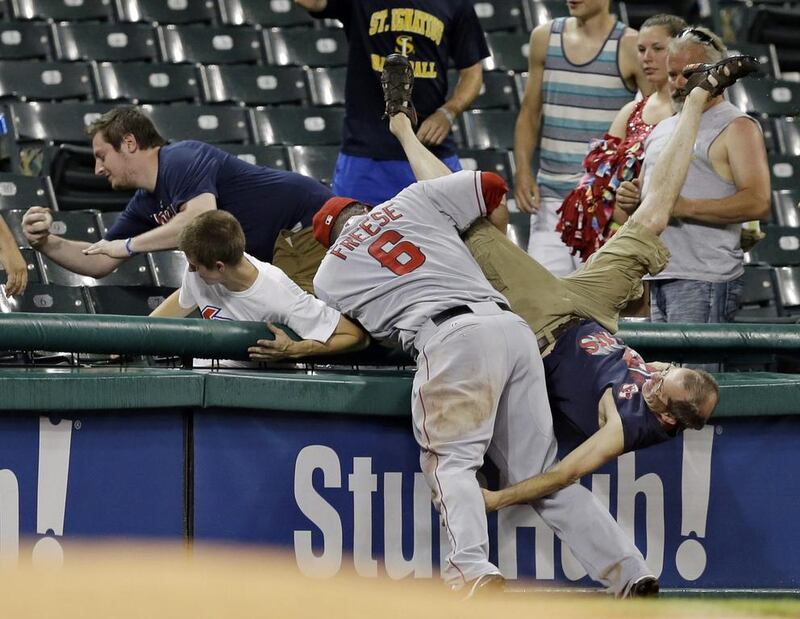 A fan falls out of the stands as Los Angeles Angels third baseman David Freese (6) tries for a pop foul by Cleveland Indians’ Carlos Santana in the ninth inning of a baseball game in Cleveland. Mark Duncan / AP 