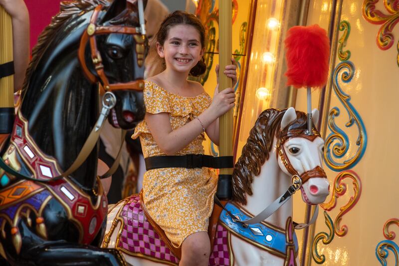 A child enjoys the Around The World Carousel in the Mobility District. Expo 2020 Dubai