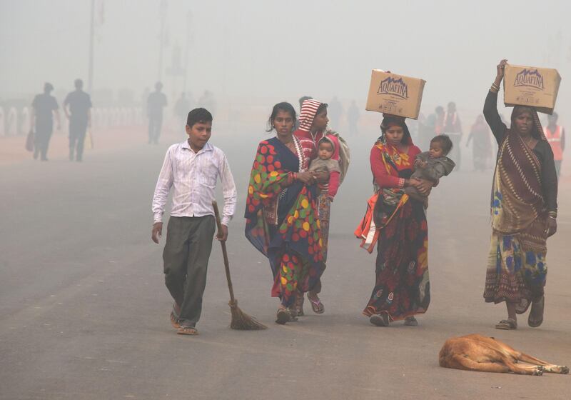 TOPSHOT - Indian residents walk along a road amid heavy smog in New Delhi on November 9, 2017.
Rickshaw driver Sanjay can only afford a handkerchief to shield his face as he weaves through the smog-filled streets of Delhi amid a rush on protection against the toxic menace. Better off residents of the global pollution black spot are swarming sellers of face masks -- that cost more than the 300 rupees ($5) that Sanjay earns in a day -- and high-tech air purifiers that could easily cost a year of his wage.
 / AFP PHOTO / DOMINIQUE FAGET / TO GO WITH India-pollution-health,FOCUS by Nick Perry