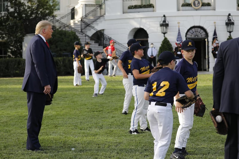 US President Donald Trump watches as youth baseball players play catch.Bloomberg